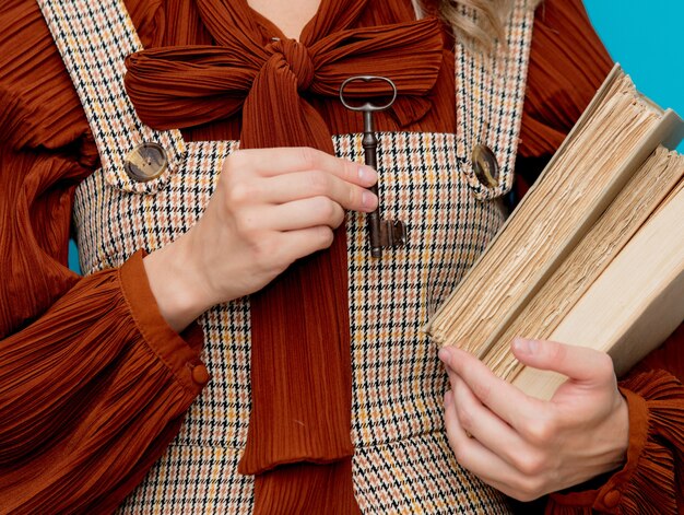 Foto jonge leraar met boeken en metaalsleutel op blauw