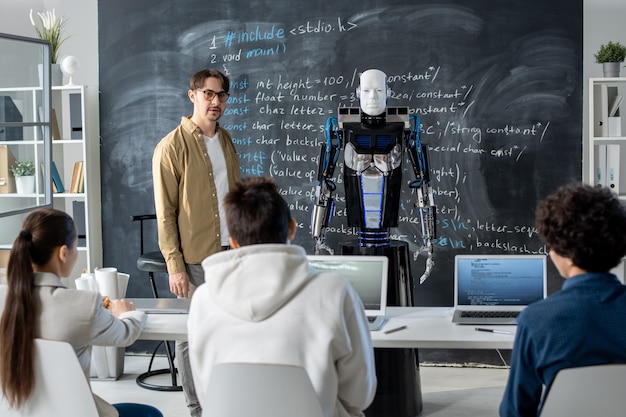 Jonge leraar permanent door bord voor publiek en presentatie van robot maken aan groep studenten op les