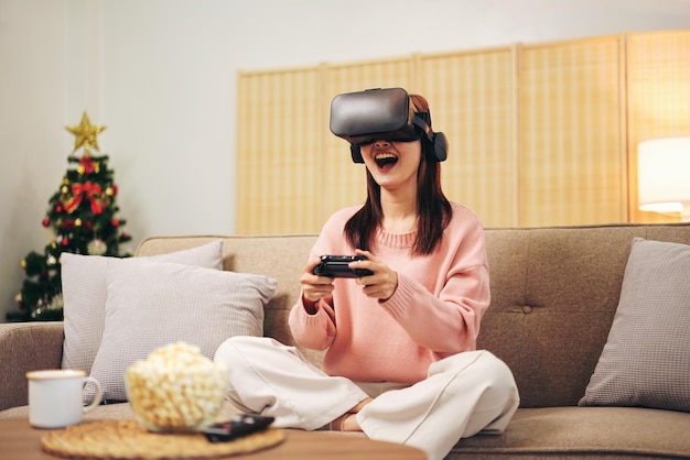 Jonge lesbische vrouw met trui en VR-bril terwijl ze de joystick vasthoudt om een videogame te spelen