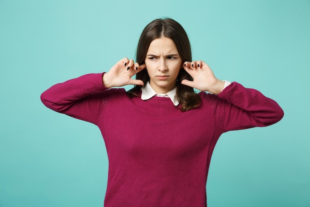 Jonge leuke verdrietig boos verbijsterd storen brunette vrouw meisje dekking oren met handen poseren geïsoleerd op blauwe muur achtergrond studio portret. mensen oprechte emoties levensstijl concept. bespotten kopie ruimte.