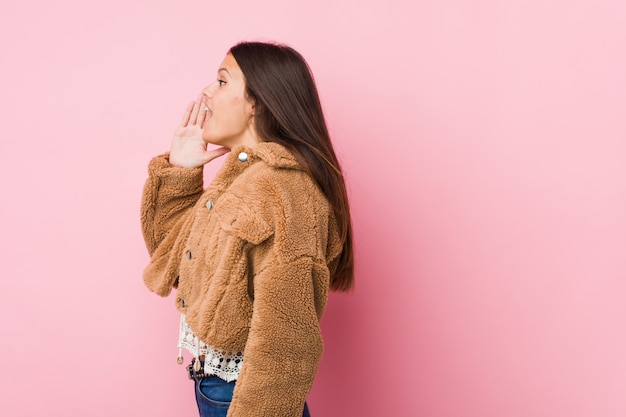 Jonge leuke vrouw die en palm schreeuwt dichtbij geopende mond houdt.