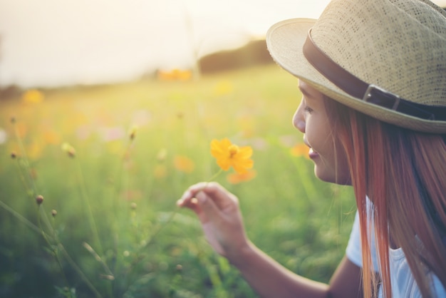 Jonge leuke vrouw die gele bloemen ruikt