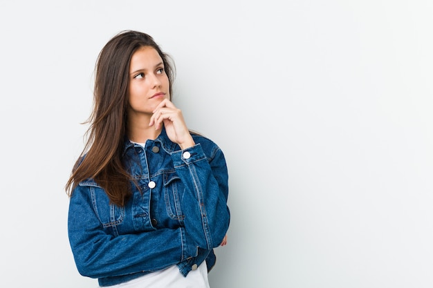 Jonge leuke vrouw die opzij kijkt met een twijfelachtige en sceptische uitdrukking.