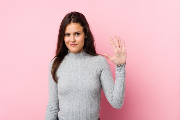 Jonge leuke vrouw die vrolijk tonend nummer vijf met vingers glimlacht.