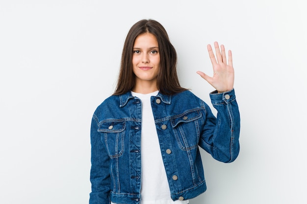 Jonge leuke vrouw die vrolijk tonend nummer vijf met vingers glimlacht.