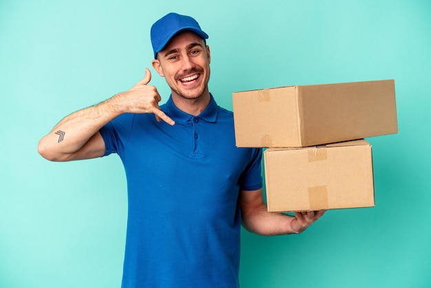 Jonge levering blanke man geïsoleerd op blauwe achtergrond met een mobiel telefoongesprek gebaar met vingers.