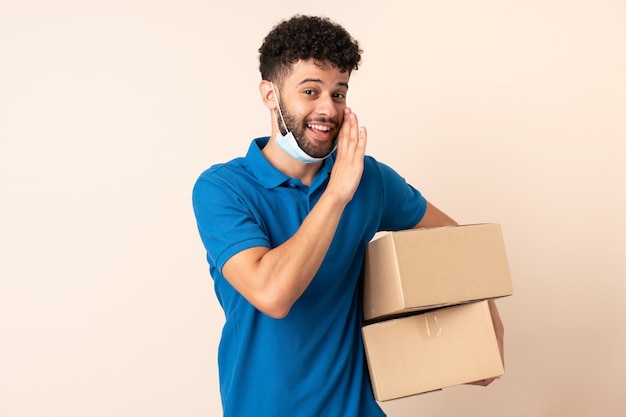 Jonge levering Marokkaanse man geïsoleerd op beige achtergrond iets fluisteren