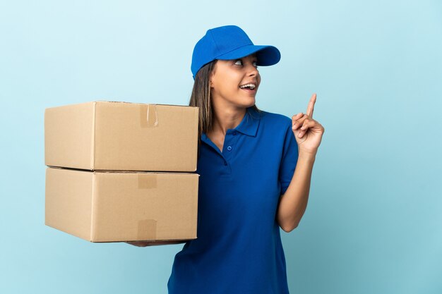 Jonge levering vrouw geïsoleerd op blauw van plan om de oplossing te realiseren terwijl het opheffen van een vinger