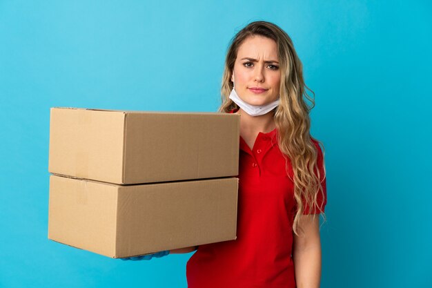 Jonge leveringsvrouw die op wit met droevige uitdrukking wordt geïsoleerd