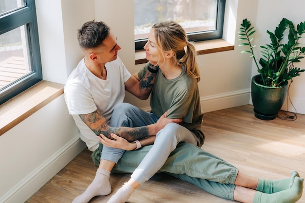 Foto jonge liefhebbende man en vrouw zitten op de vloer in de woonkamer.