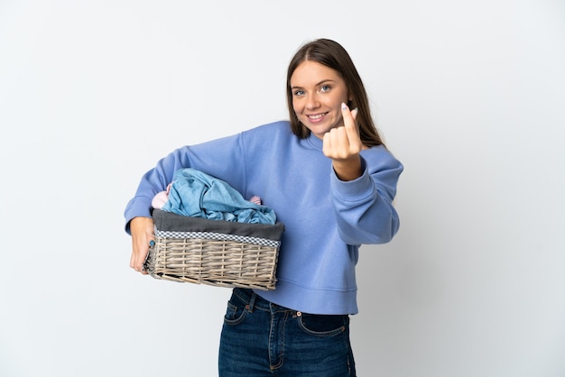 Jonge Litouwse vrouw die een wasmand houdt die op witte achtergrond wordt geïsoleerd die geldgebaar maakt