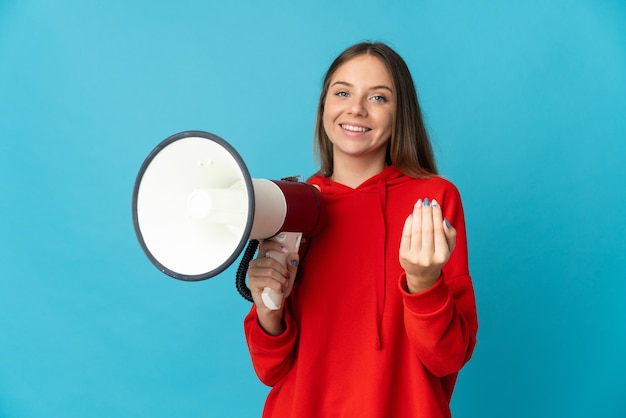 Jonge Litouwse vrouw die op blauwe muur wordt geïsoleerd die een megafoon houdt en uitnodigt om met de hand te komen