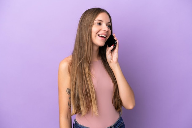 Jonge Litouwse vrouw geïsoleerd op een paarse achtergrond die een gesprek voert met de mobiele telefoon