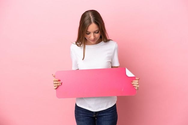 Jonge Litouwse vrouw geïsoleerd op roze achtergrond met een leeg bordje