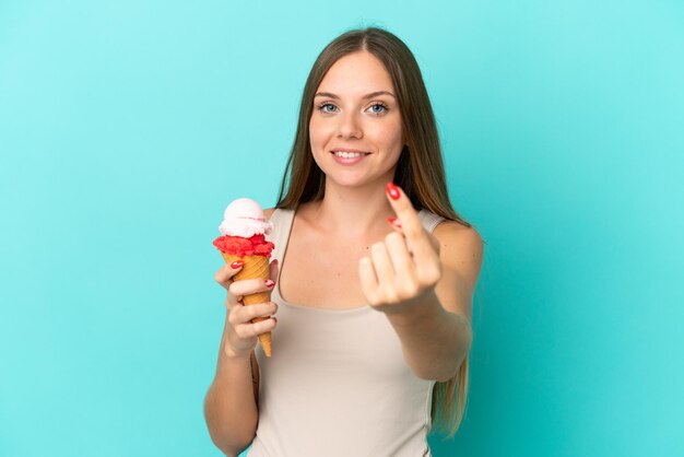 Jonge Litouwse vrouw met cornet-ijs geïsoleerd op blauwe achtergrond die komend gebaar doet