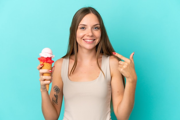 Jonge Litouwse vrouw met cornet-ijs geïsoleerd op een blauwe achtergrond die een duim omhoog gebaar geeft