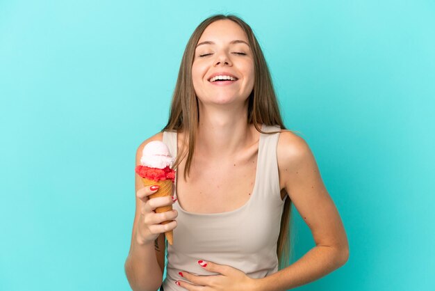 Jonge Litouwse vrouw met cornet-ijs geïsoleerd op een blauwe achtergrond die veel lacht