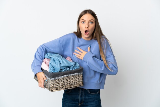 Jonge Litouwse vrouw met een wasmand geïsoleerd op een witte achtergrond verrast en geschokt terwijl ze naar rechts kijkt