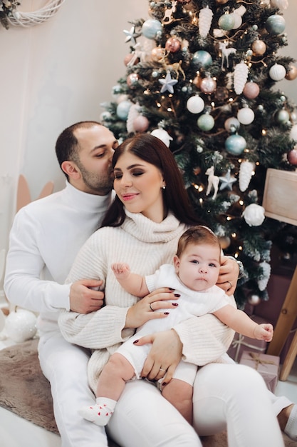 Jonge mama en papa met kind in witte kleren die samen zitten