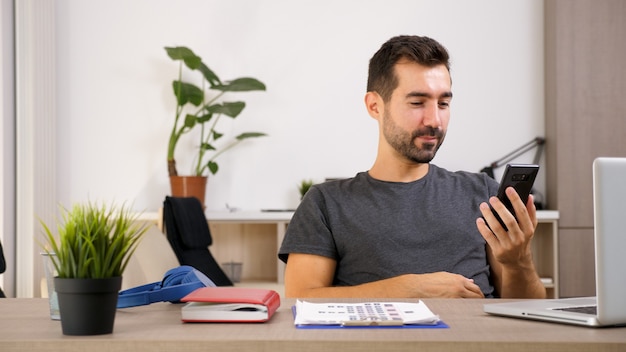 Jonge man aan de telefoon terwijl hij op kantoor is. Slimme man die voor zaken zorgt.