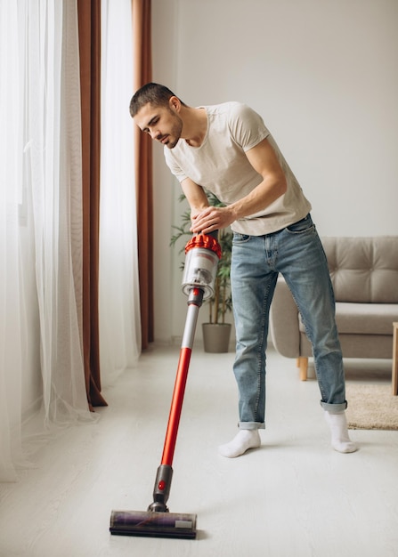 Jonge man aan het stofzuigen in het appartement