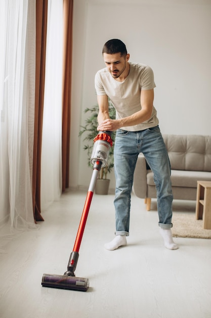 Jonge man aan het stofzuigen in het appartement