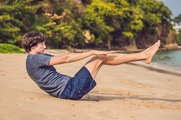 Jonge man aan het trainen op het strand, sportieve man die oefeningen doet