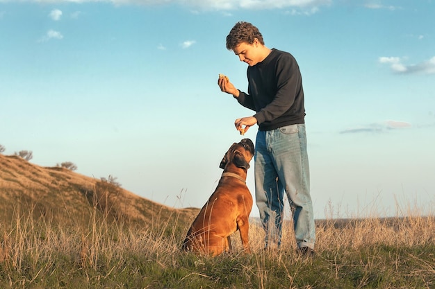 jonge man aan het wandelen met zijn grote hond die fastfood eet