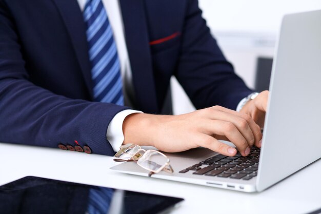 Jonge man aan het werk met laptopcomputer, man's handen op notebook, zakenman op de werkplek.