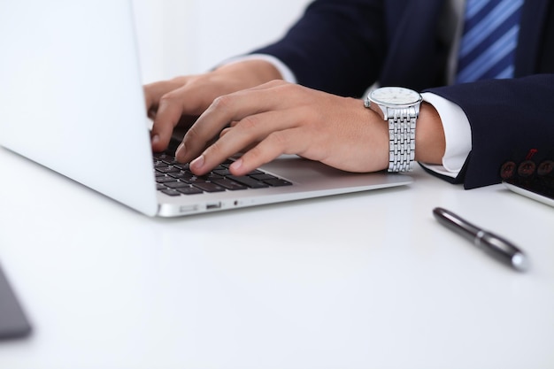 Jonge man aan het werk met laptopcomputer, man's handen op notebook, zakenman op de werkplek.