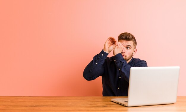 Jonge man aan het werk met zijn laptop op zoek ver weg houden hem hand op het voorhoofd.