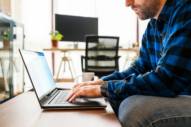 Jonge man aan het werk met zijn laptop vanuit zijn woonkamer. Blijf thuis, werk vanuit huis concept