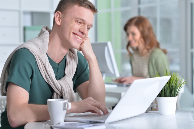 Jonge man aan het werk op kantoor met een laptop