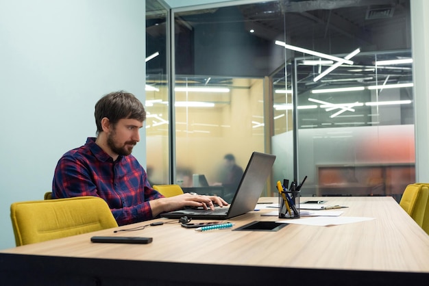 Jonge man aan het werk op laptop in modern coworking kantoor