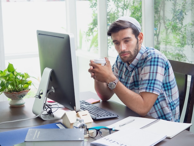 Jonge man aan het werk thuis met koffie