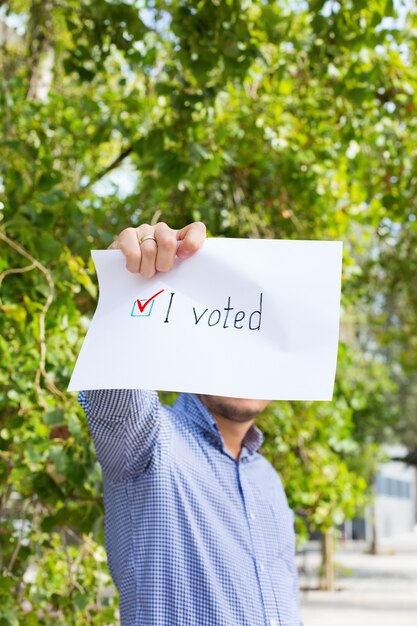 Jonge man, activist roept op om te stemmen met papier in handen met de verklaring dat ik heb gestemd. politiek activisme, verkiezingsproces, concept van actieve levensposities. voorzitter, grondwetsverkiezingen.