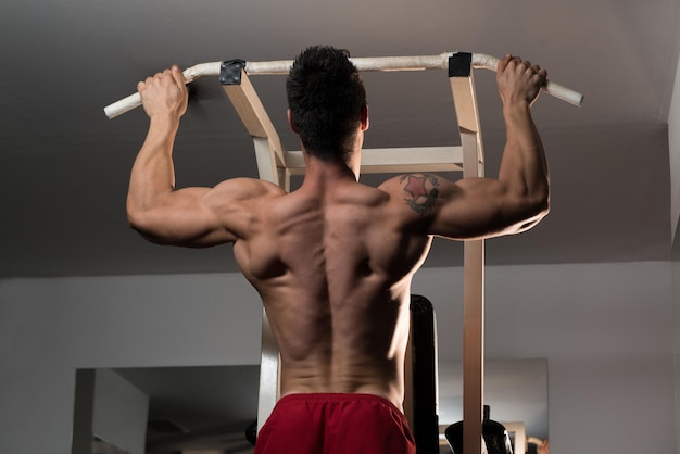 Jonge man atleet doet pull-ups ChinUps in de sportschool