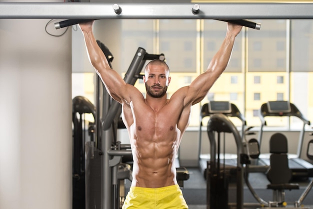 Jonge man atleet doet pull-ups ChinUps in de sportschool