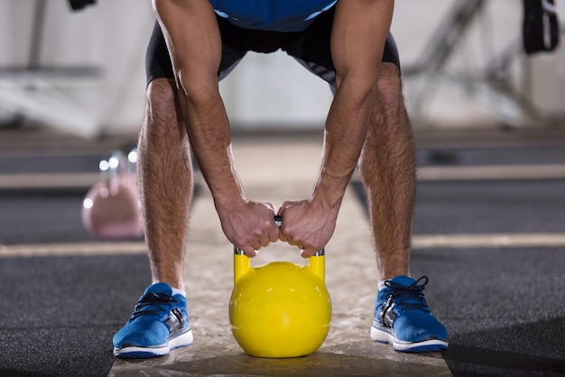 jonge man atleet oefening met fitness kettlebell bij cross fitness gym
