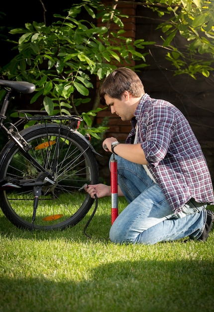 Jonge man banden op zijn fiets oppompen in park