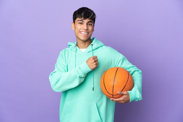 Jonge man basketbal spelen over geïsoleerde paarse muur een overwinning vieren