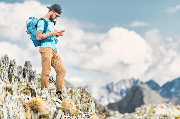 Jonge man behandelt smartphone tijdens in alpine trektocht