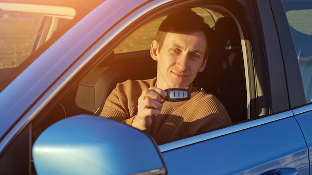 Jonge man bestuurder met afstandsbediening sleutel zittend in auto