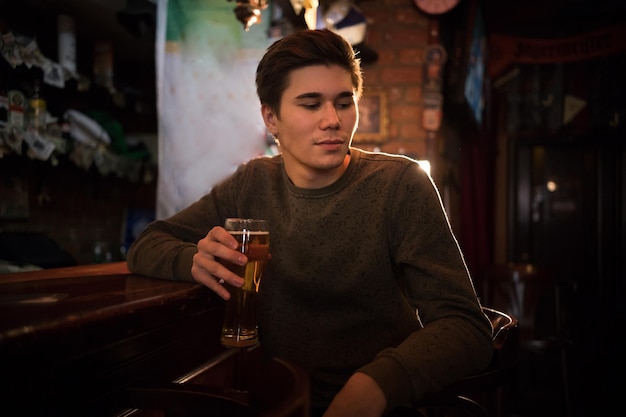 Jonge man bier drinken aan de bar op zoek naar de zijkant?