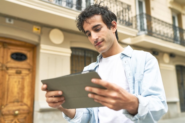 Jonge man blijft verbonden en productief terwijl hij onderweg surft en geniet van zijn tablet