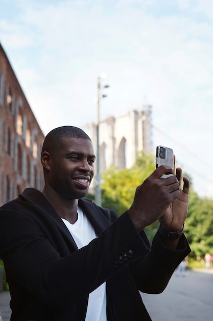 Foto jonge man buitenshuis die de stad alleen verkent en foto's maakt met smartphone