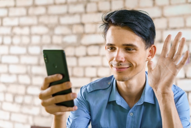 Jonge man communiceert via videocommunicatie via de telefoon. Man in blauw shirt