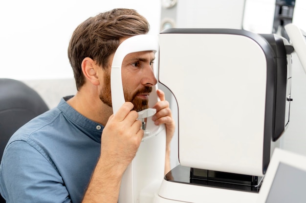 Foto jonge man controleert zijn gezichtsvermogen met een autorefractor in een optiekwinkel