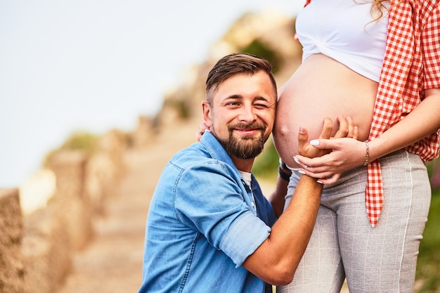 Jonge man die aan de buik van zijn zwangere vrouw luistert