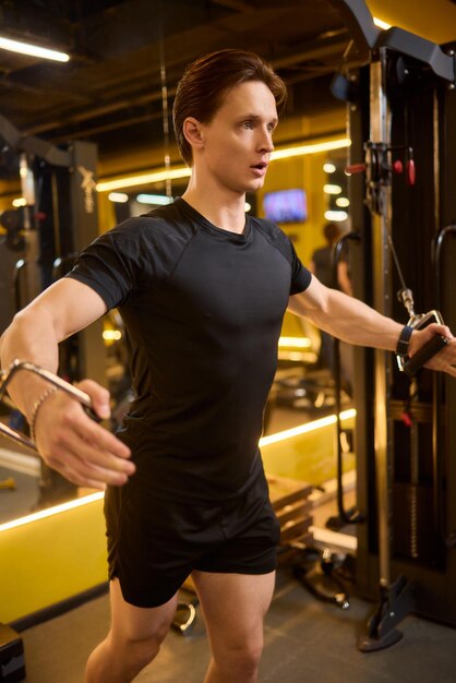 Jonge man die aandachtig traint in de sportschool met een kabelmachine voor weerstandstraining